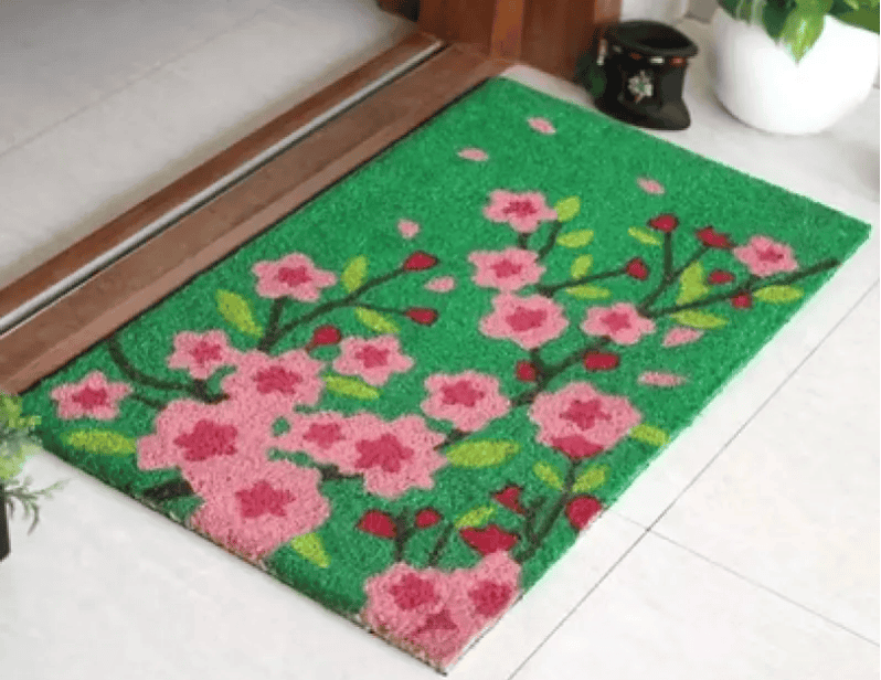 Colorful floral door mat with pink blossoms and green leaves, ideal for garden or outdoor decor.
