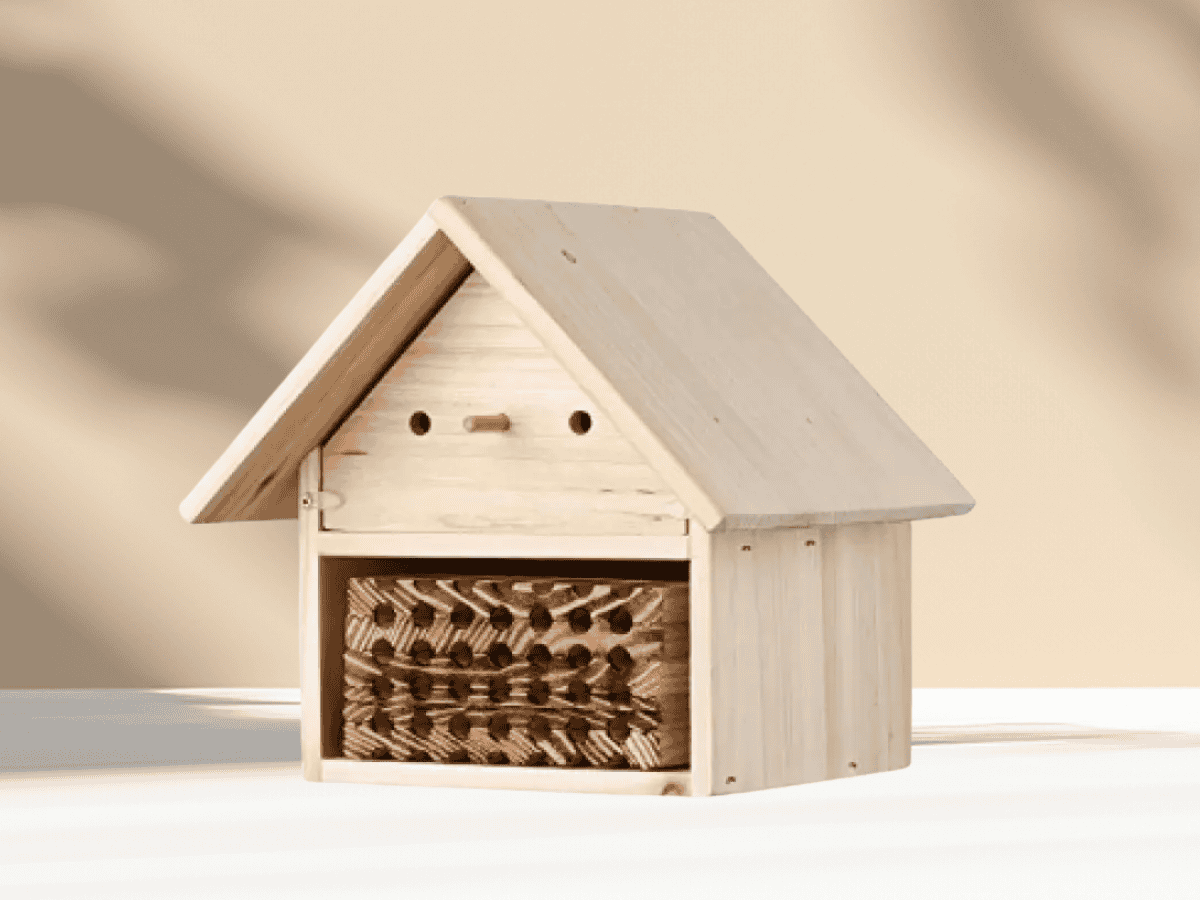 Natural wooden insect hotel with multiple holes for bees and beneficial insects, ideal for garden habitat enhancement.