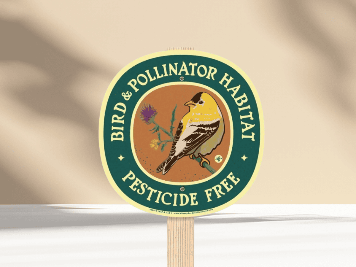 Colorful bird and flower garden sign promoting pesticide-free pollinator habitat.