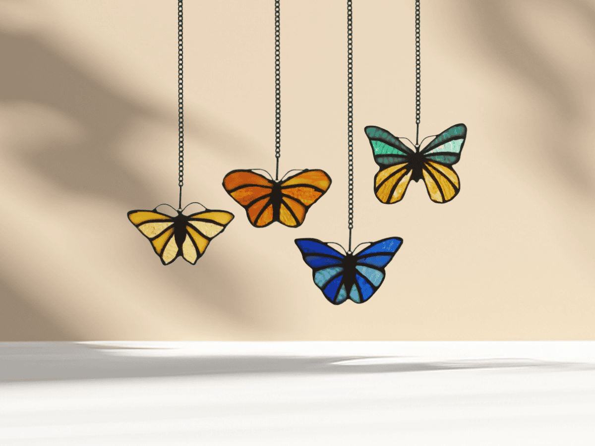Vivid stained glass butterfly mobile hanging on a wall, perfect for garden or home decor enthusiasts.